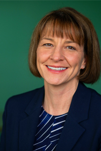 kim love head shot against green background smiling eye contact