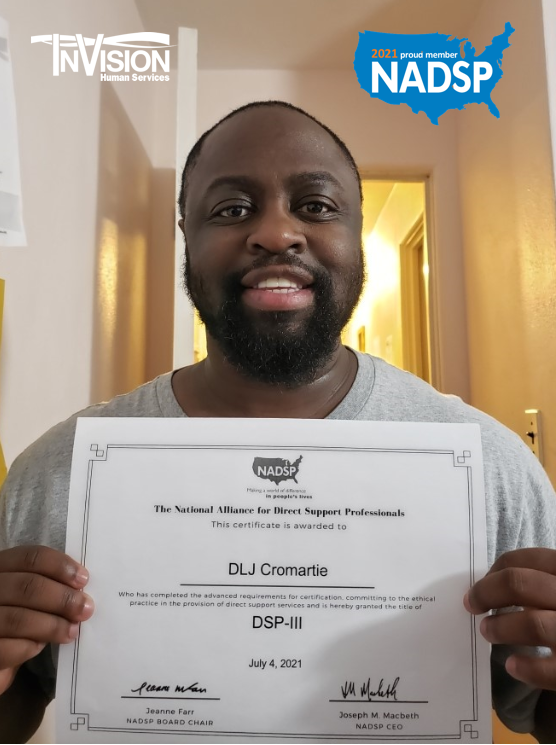 DLJ Cromartie smiling while holding his National Alliance for Direct Support Professionals certificate in front of his chest