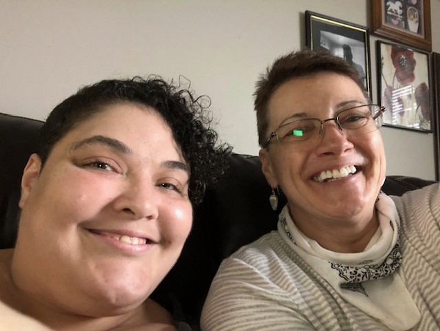 Vicki Fountain and a woman she supports sitting on a couch smiling with their heads close together in a selfie