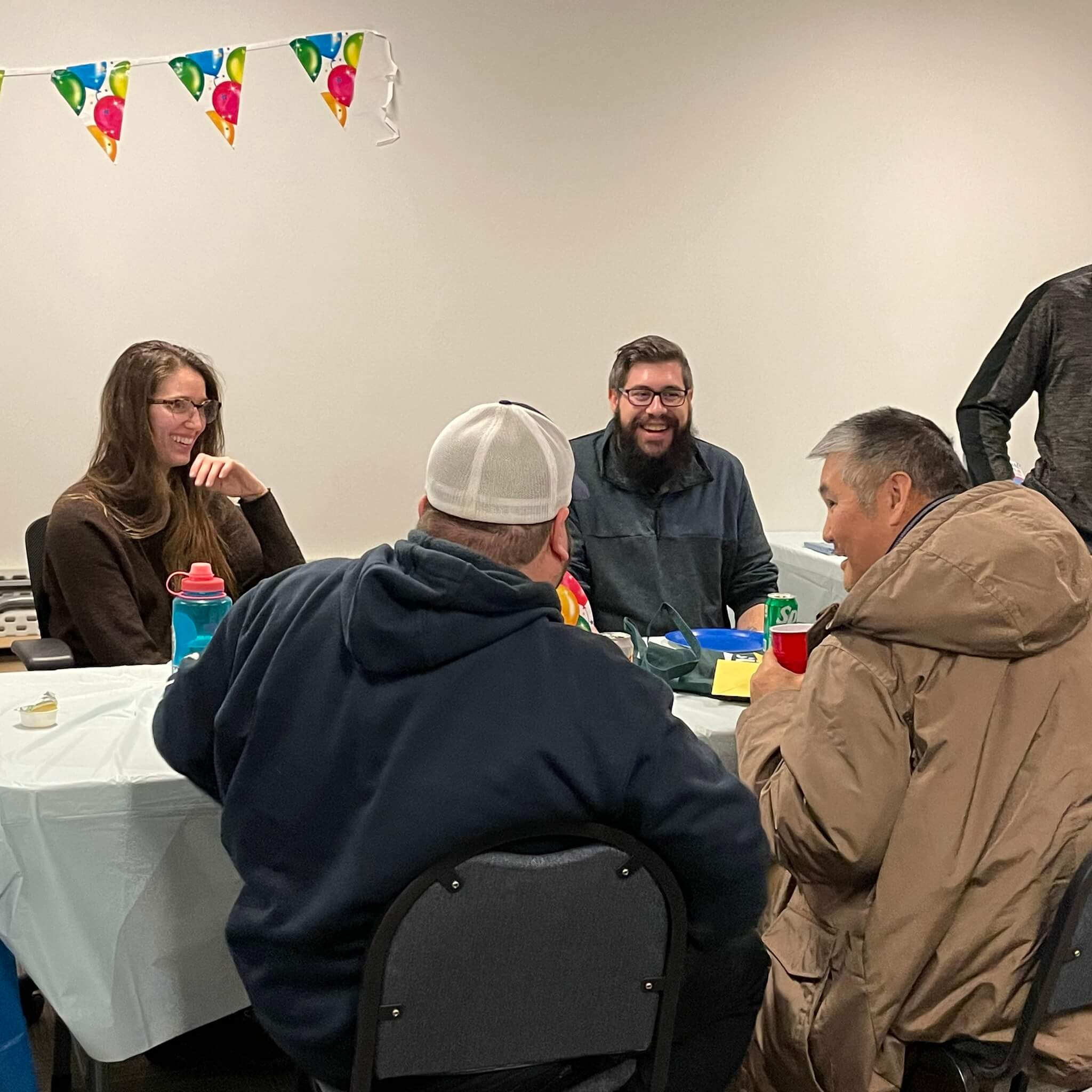 four people sitting at a table at a birthday party chatting happily