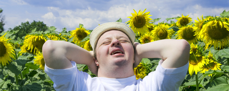 Man with Down syndrome in field of sunflowers emotional